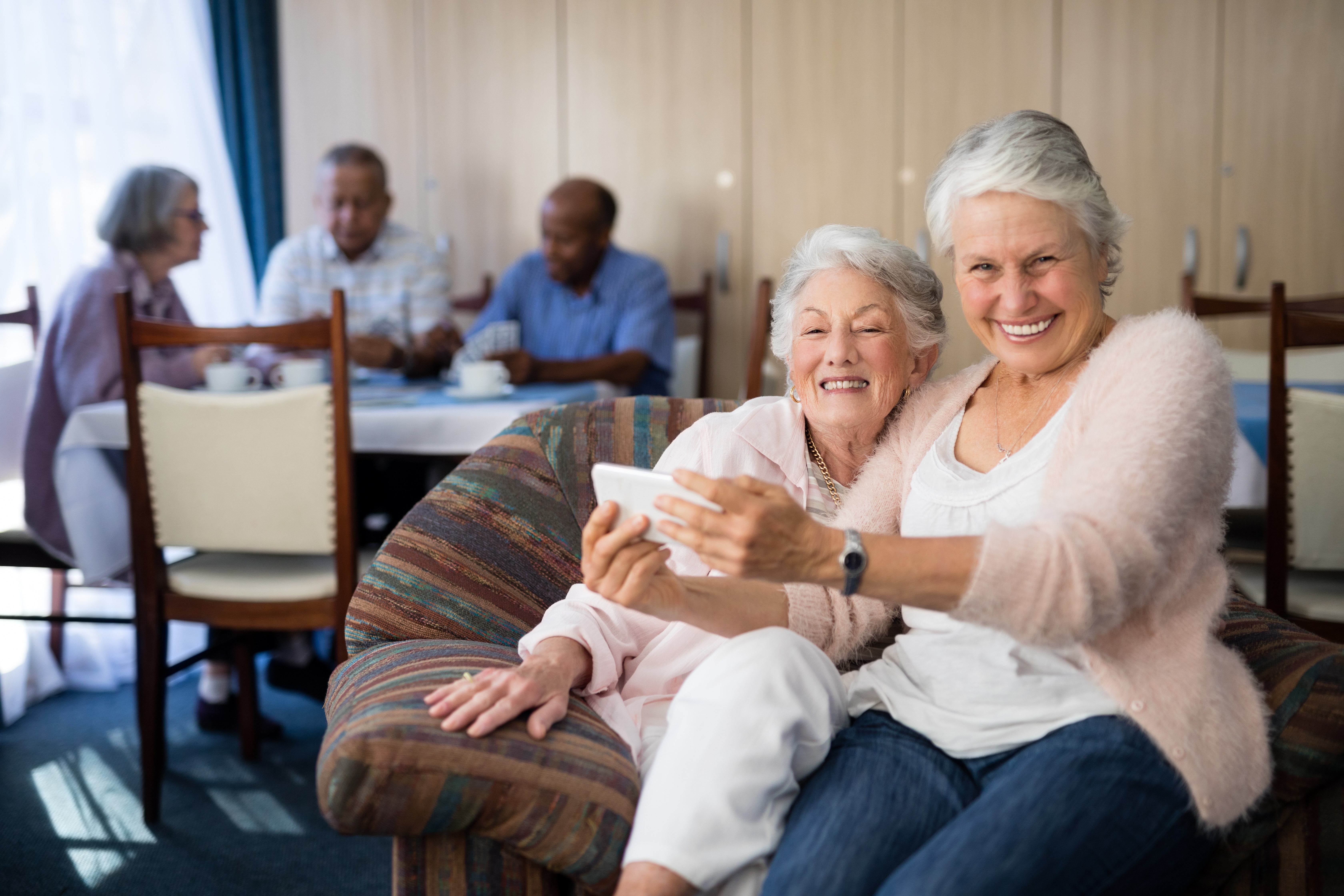 two older women sitting together smiling in a senior living community 