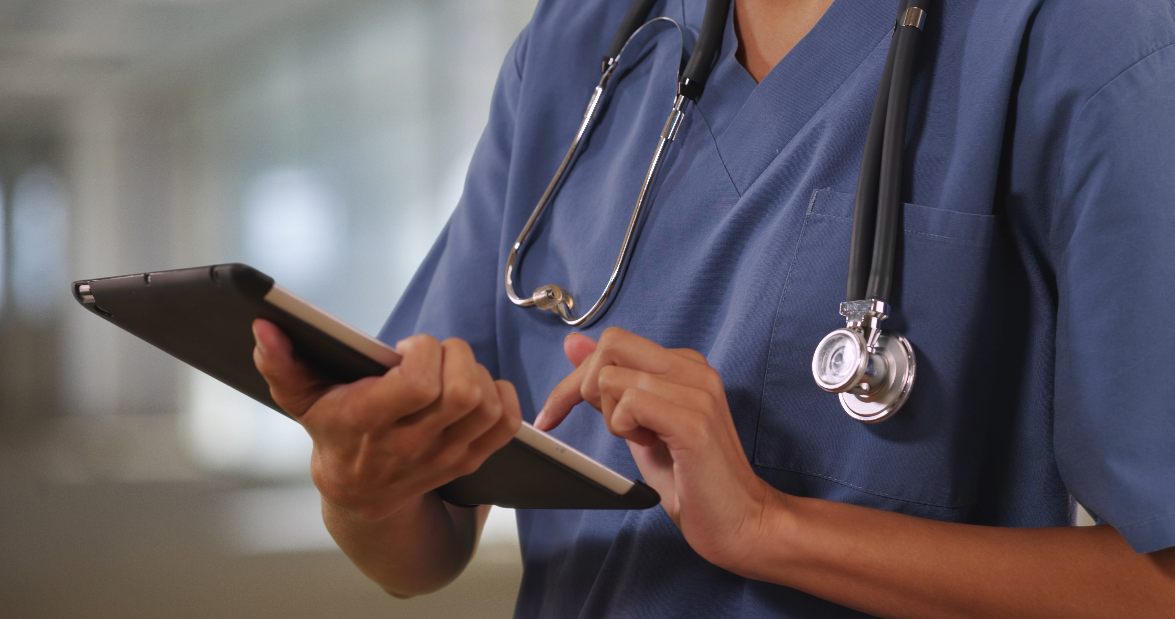 a nurse in blue scrubs responds to a remote patient monitoring notification on a tablet 