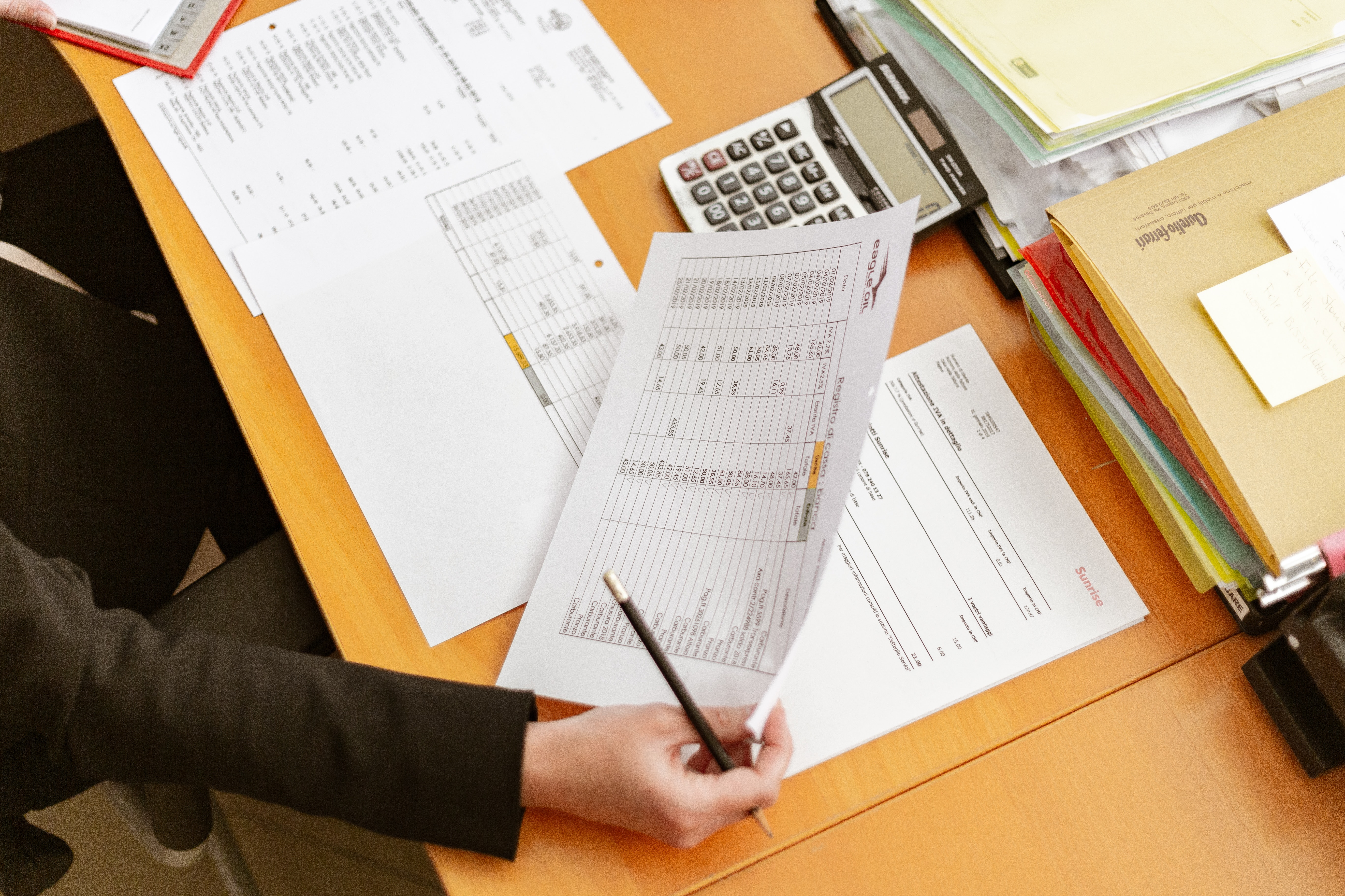 A desk scattered with financial documents, a calculator, and invoices. 